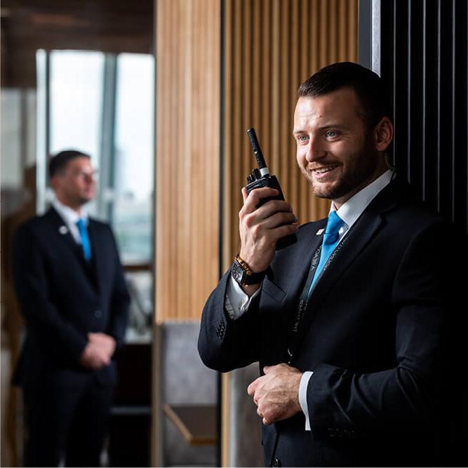 Two male suited security guards using mobile radios